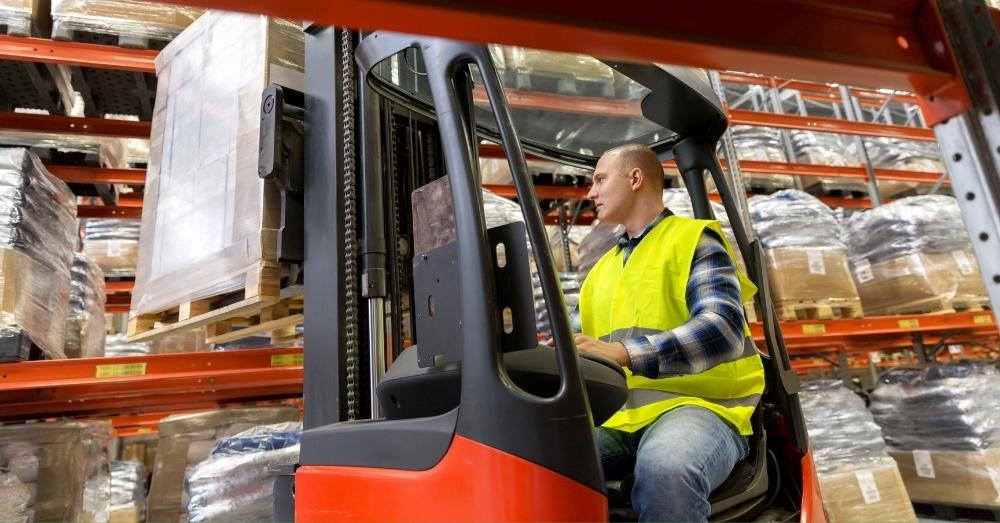 A forklift driver works in a busy warehouse.