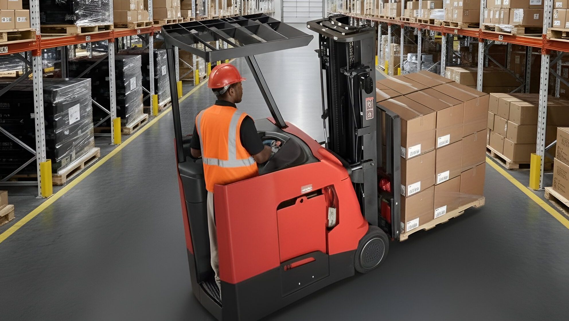 Warehouse worker in a safety vest and hard hat operating a red reach truck carrying a pallet of boxes down a pallet-racked aisle — reach truck.
