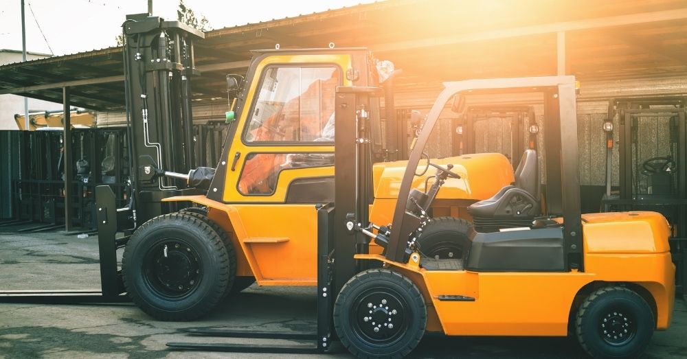 Two bright yellow forklifts are parked side-by-side.