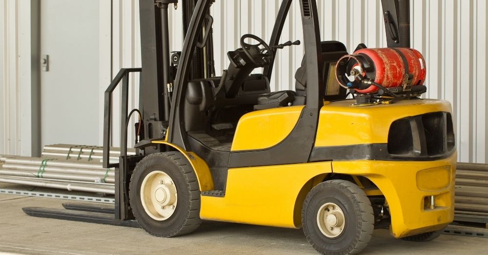 A bright yellow forklift with black accents is parked in a warehouse.