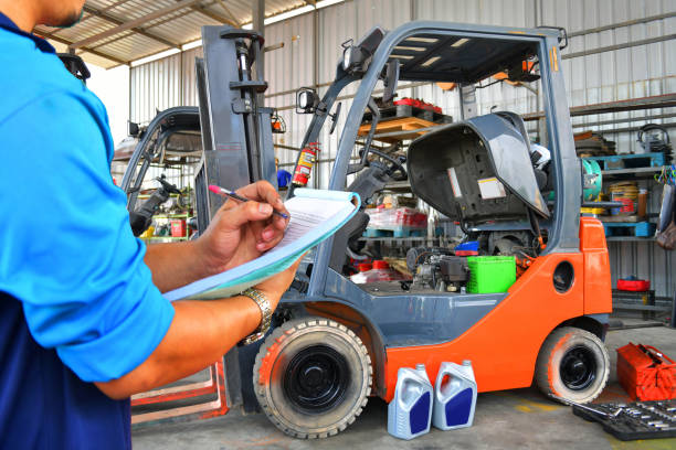Mechanic performing a maintenance inspection on a forklift in a workshop