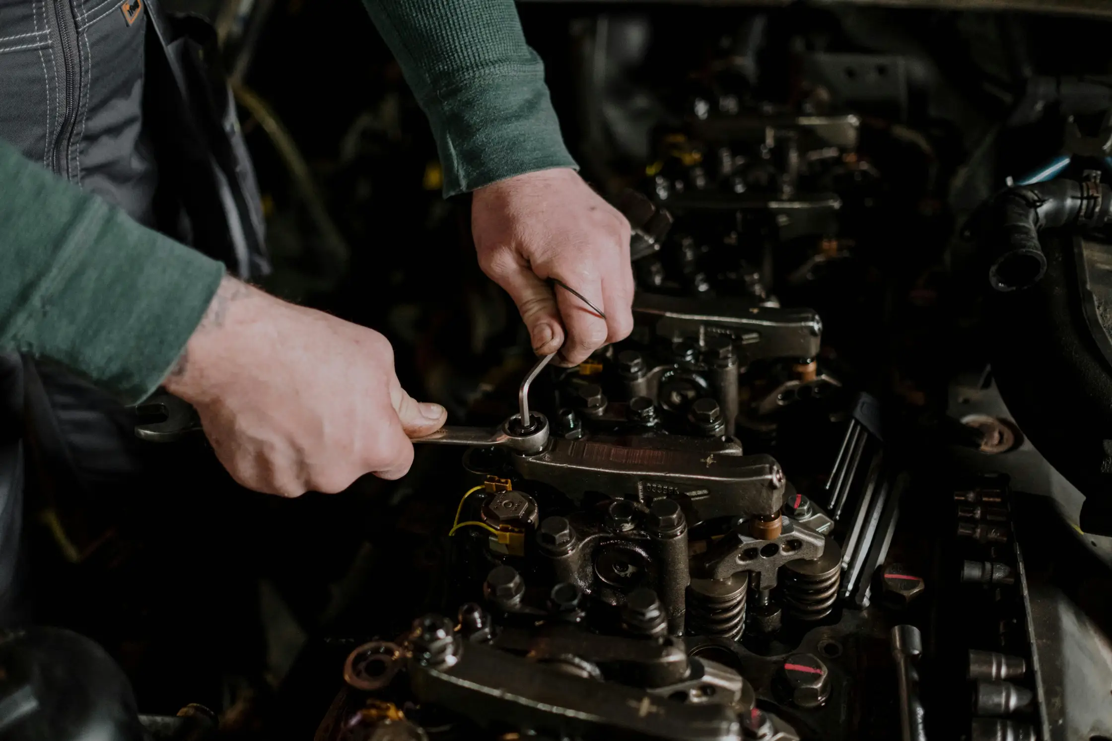 Close-up of a mechanic using wrenches to adjust engine components during car engine repair and maintenance