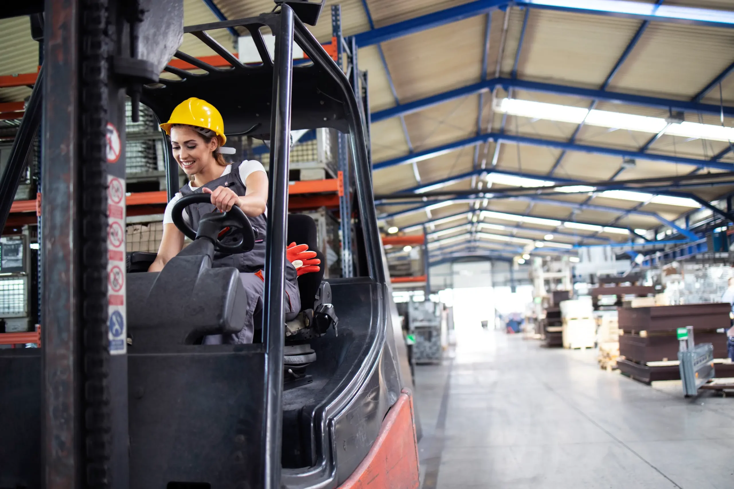 Female forklift operator in a warehouse adjusting forklift controls